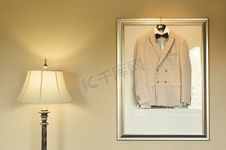 婚礼墙摄影照片_一间带台灯的房间的壁灯上挂着一件轻便的喜庆婚礼夹克