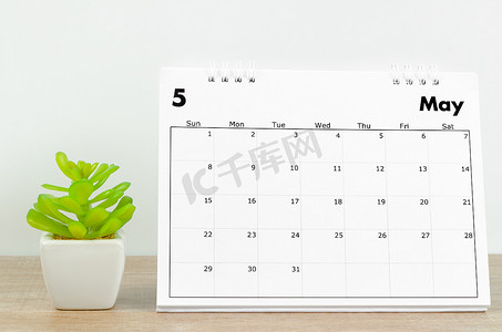 5月份摄影照片_2022 年 5 月台历，木桌上有植物。