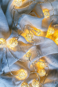 织物褶皱上带有球灯的花环背景