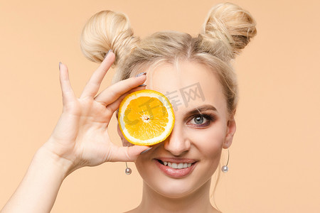一位美丽甜美、清新亮丽、发型酷炫的女性手里拿着两片橙子片，夏天、欢乐、明亮的广告复制空间