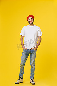 年轻的时髦男人戴着帽子，背带裤，在黄色背景上隔离。