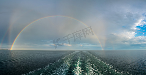 海上游轮的尾迹上形成了戏剧性的双彩虹