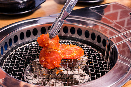 韩国烤肉摄影照片_烤肉猪肉韩国烧烤传统风格在炉子上供应餐厅