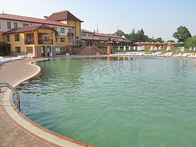 豪华酒店大楼，入口处设有游泳池，配有供放松身心的白色日光浴床