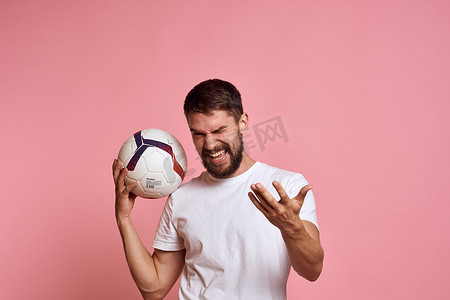 指手画脚的人摄影照片_在粉红色背景能量上拿着足球的男人用他的手教练情绪模型指手画脚