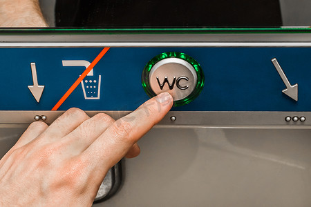 在施泰德勒电动火车的现代厕所里，一个男人的手按着冲水按钮，特写