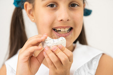 治疗完成后，青少年在正畸治疗开始时将牙齿模型放在牙齿旁边。