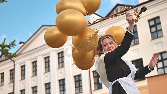 快乐的俄罗斯女学生在学校的最后一天拿着气球。