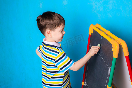 男孩用粉笔在黑板上画画。