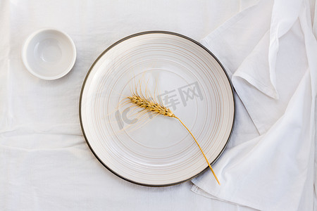 桌子上的空盘子里放着一穗谷粒。