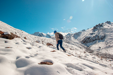 山顶云摄影照片_一个人在冬天从雪坡上爬到山顶。