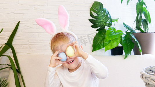 有复活节彩蛋和跳舞的兔子耳朵的滑稽的愉快的孩子男孩。