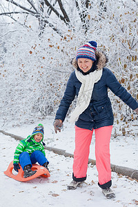 家庭在冬季公园玩雪橇