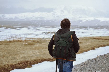 现实山摄影照片_男人背着背包，看着冬天的山