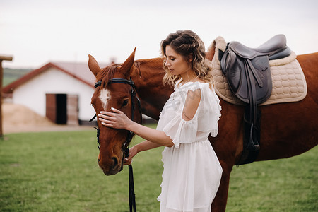 庄园牧场摄影照片_一个白色太阳裙的美丽的女孩在一个老牧场的一匹马旁边