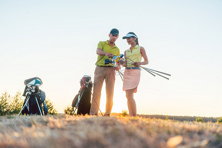教室外摄影照片_高尔夫教练教一位年轻女子如何使用不同的高尔夫球杆