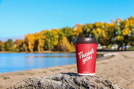 红纸蒂姆·霍顿的一杯咖啡，在自然早晨的背景下写着“谢谢”
