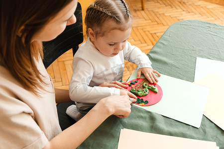 母亲和小女儿为幼儿园制作工艺品，享受一个充满创意的早晨。