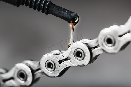 齿轮上的油摄影照片_在孤立的灰色背景上用一滴油特写润滑自行车链条