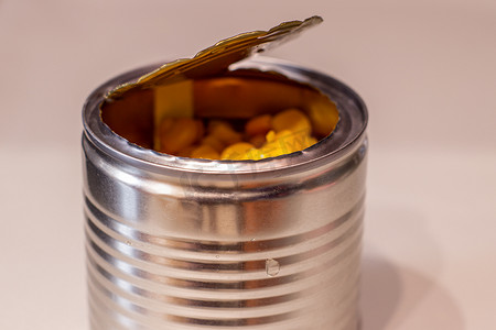 打开金属罐头用在白色背景的甜玉米。