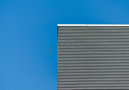 蓝色晴空下灰色高楼的条纹墙