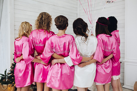 丝绸背摄影照片_身穿粉红色丝绸长袍的伴娘，背上写着“伴娘”字样