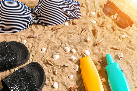 夏季比基尼及配饰时尚海滩套装、海滩比基尼夏季服装和海沙为背景、顶视图、概念