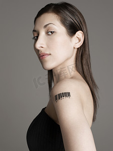 灰色背景下手臂上有条形码纹身的年轻女子的肖像