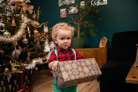 圣诞节那天，一个两岁的小男孩拿着一个礼物包。
