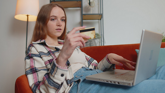 坐在家里使用信用卡和笔记本电脑的女性在网上购物时转账