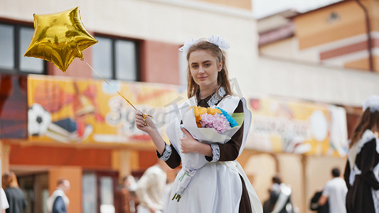 最后一天摄影照片_快乐的俄罗斯女学生在学校的最后一天拿着气球。