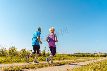 夏天，两个健康的老年人在乡间小路上慢跑