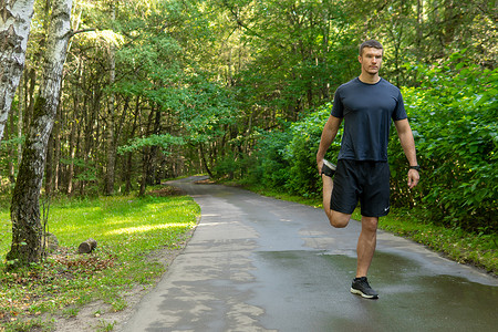 一名男子运动员在户外公园跑步，在森林周围，橡树绿草年轻持久的运动员活跃的运动员自然，健身慢跑者训练健康男性，秋季休闲跑步，脚伸展