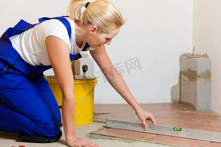 女性铺瓷砖工在地板上铺瓷砖