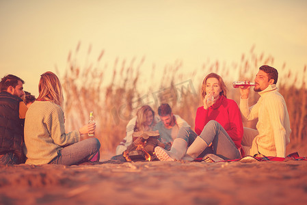 一对夫妇在日落时分在海滩上与朋友一起享受