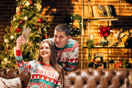 快乐的白人男女夫妇在家里装饰着圣诞树在线视频聊天，并向亲朋好友致以节日问候。