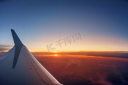 飞机机翼摄影照片_充满活力的日落期间的飞机机翼