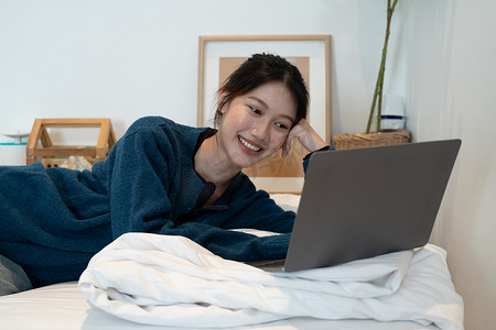 可爱的亚洲女孩在她的笔记本电脑上看电影。