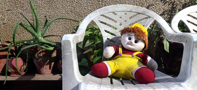印度后院的塑料椅子上坐着一个毛绒娃娃