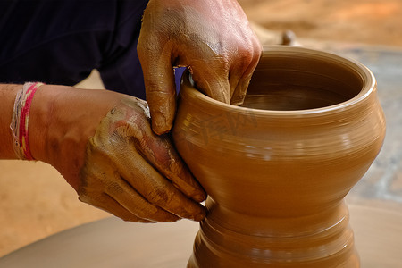 陶器-陶工熟练的湿手在陶轮上塑造粘土