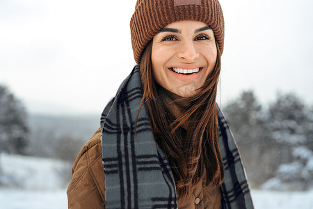 穿着冬季保暖夹克的女人在多雪的冬季森林里行走