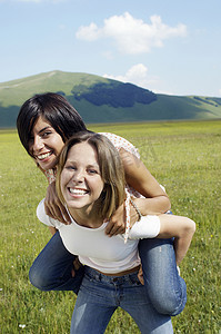 公园里快乐的年轻女子背着女性朋友的肖像