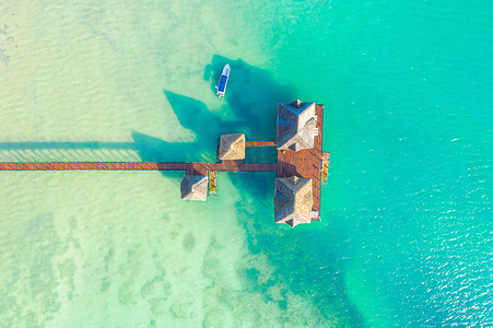 从无人机俯瞰马尔代夫的一个豪华热带岛屿天堂度假村，那里有木码头和带桌椅的休闲区