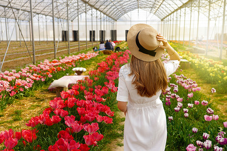 美丽的女孩拿着草帽在花间行走，准备在日落时野餐。