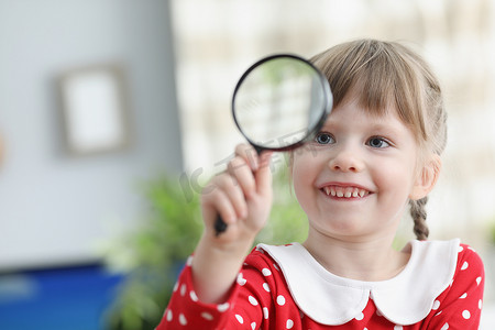 放大镜小孩摄影照片_漂亮的小孩拿着放大镜，通过它探索世界