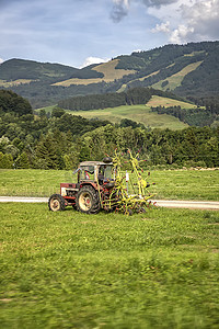 农业机械，拖拉机在蓝天的映衬下在田野里收草。