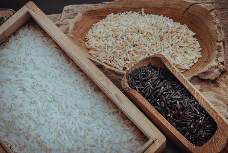 各种类型的大米：糙米、茉莉花米、旧木背景上的 Riceberry。