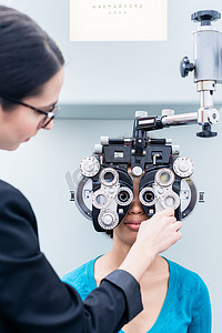 配镜师和妇女用综合屈光仪进行眼科检查