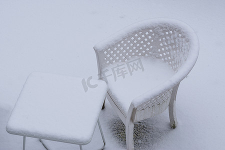 厚厚的雪摄影照片_冬季，白色桌子和躺椅被厚厚的雪覆盖，冬季花园休息室