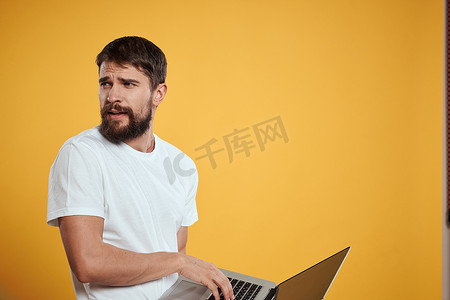 一个留着胡子的男人手里拿着一台笔记本电脑，上面是黄色背景键盘显示器新技术的侧视图